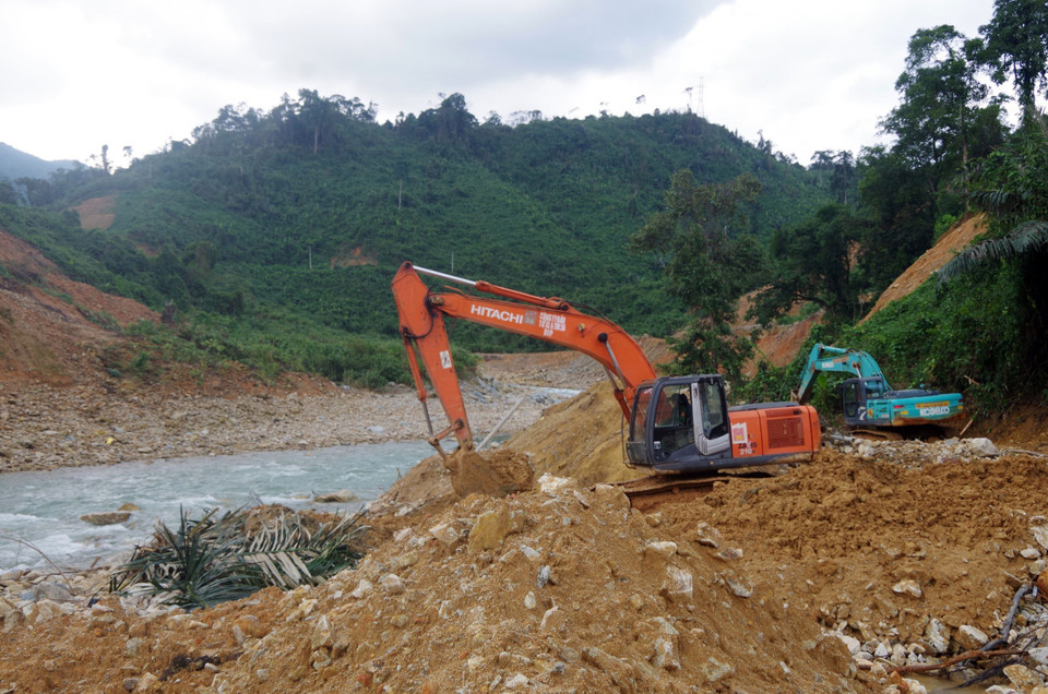  Lực lượng cơ giới múc đất đá, tạo dòng chảy mới phục vụ cho việc nắn dòng suối Rào Trăng. (Ảnh: TTXVN phát)
