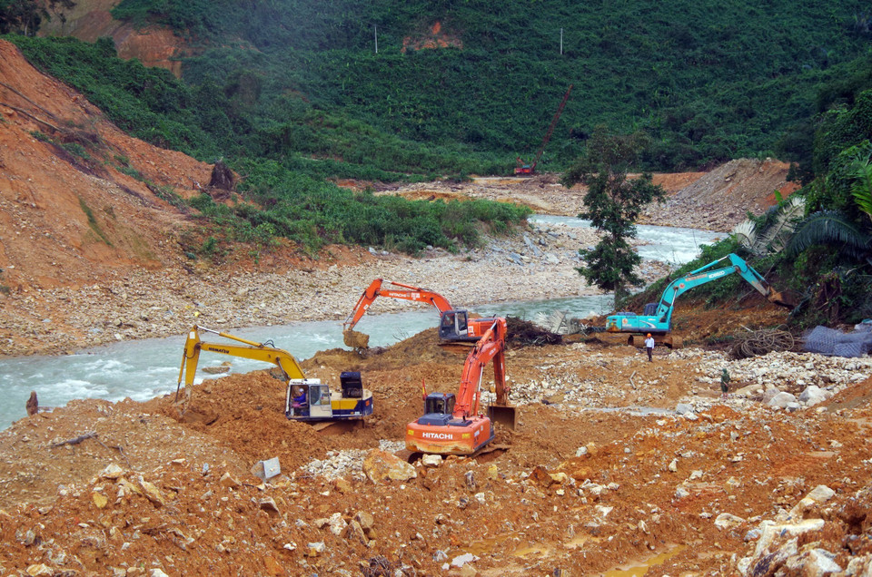  Lực lượng cơ giới múc đất đá, tạo dòng chảy mới phục vụ cho việc nắn dòng suối Rào Trăng. (Ảnh: TTXVN phát)