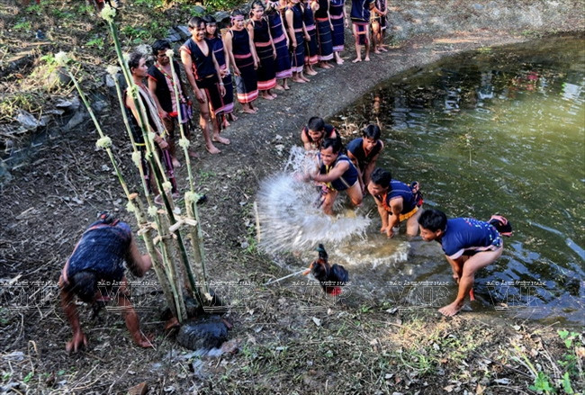 Dân làng tiến hành nghi lễ dùng tay té nước vào con gà và chàng thanh niên to khỏe. (Nguồn: Trịnh Bộ/Báo ảnh Việt Nam)