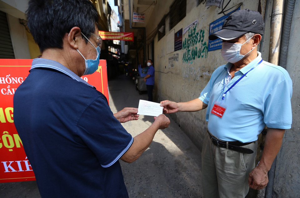 Thực tế đã chứng minh trong nhiều đợt dịch, tổ COVID cộng đồng hoạt động vô cùng hiệu quả, góp phần đặc biệt quan trọng trong việc kiểm soát và đẩy lùi dịch bệnh. Trong ảnh: Tổ phòng, chống COVID cộng đồng phường Cầu Dền, quận Hai Bà Trưng kiểm tra thẻ đi chợ của người dân. (Ảnh: Hoàng Hiếu/TTXVN)