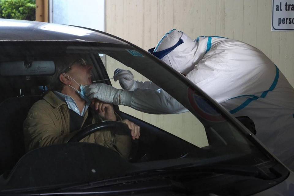 Nhân viên y tế mặc đồ bảo hộ kiểm tra một người ngồi trong xe hơi. (Nguồn: EPA-EFE)