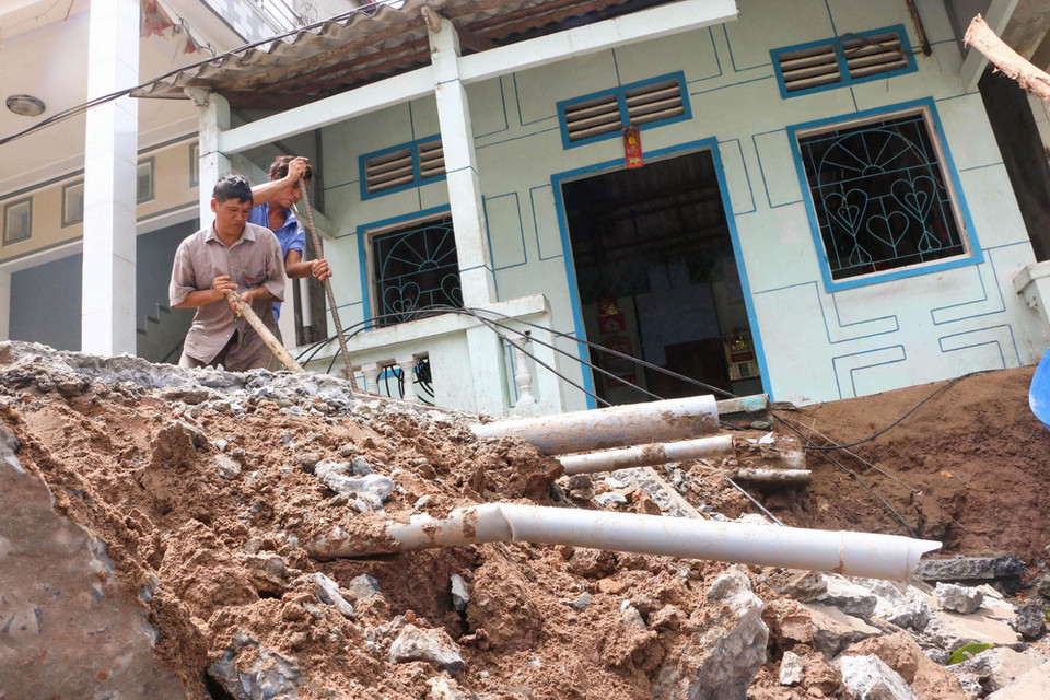 Người dân cố gắng ngăn chặn nước sông sói lở thêm vào nền nhà. (Ảnh: Duy Khương/TTXVN)