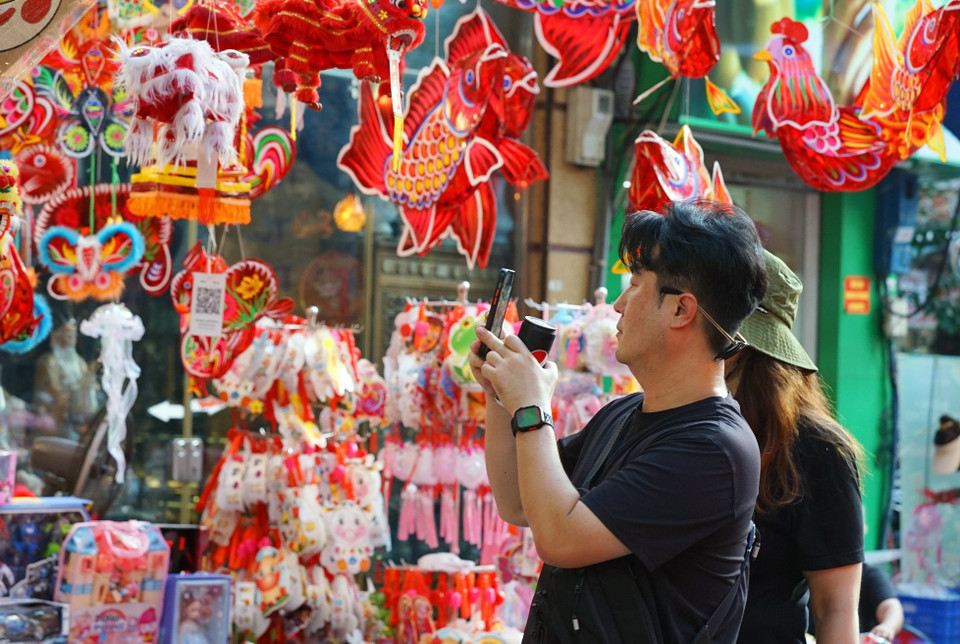 Du khách nước ngoài thích thú lưu lại hình ảnh các món đồ chơi Trung Thu truyền thống trên phố Hàng Mã. (Ảnh: Khánh Hòa/TTXVN)