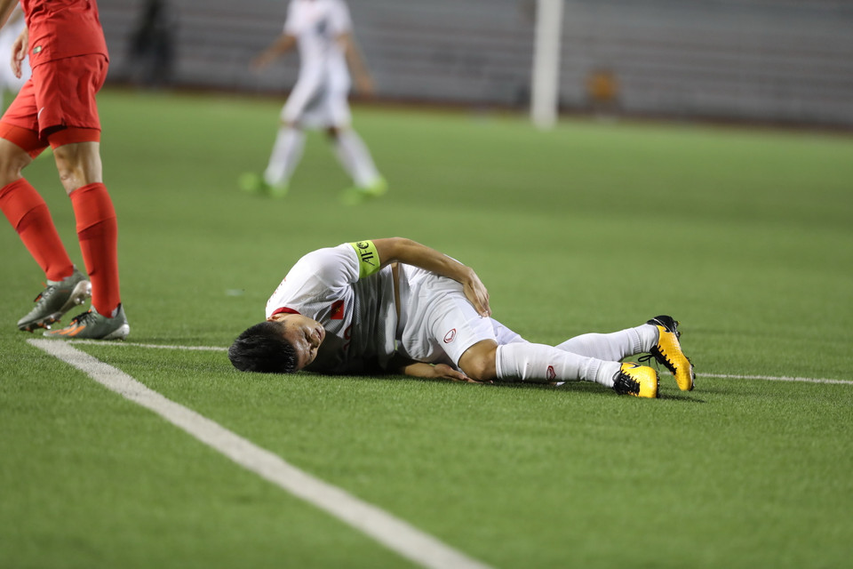 Sự quyết liệt của U22 Singapore khiến Quang Hải bị đau sau một pha tranh chấp... (Ảnh: Hoàng Linh/TTXVN)