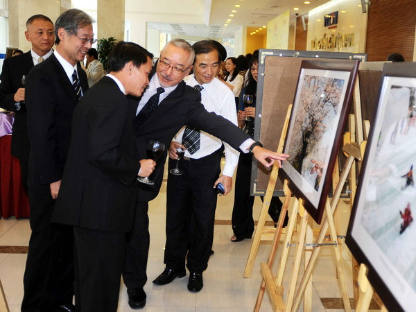 Tổng Giám đốc TTXVN Nguyễn Đức Lợi, Chủ tịch Hãng Thông tấn Kyodo Nhật Bản, ông Masaki Fukuyama cùng các đại biểu xem ảnh được trưng bày tại triển lãm. (Ảnh: Minh Đức/TTXVN)