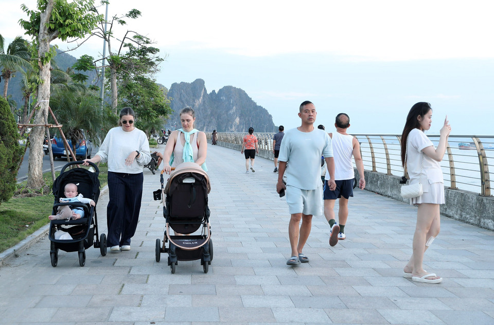 Khách du lịch quốc tế tản bước trên vỉa hè đường Trần Quốc Nghiễn và có thể ngắm nhìn Di sản Vịnh Hạ Long. (Ảnh: Quốc Khánh/TTXVN)