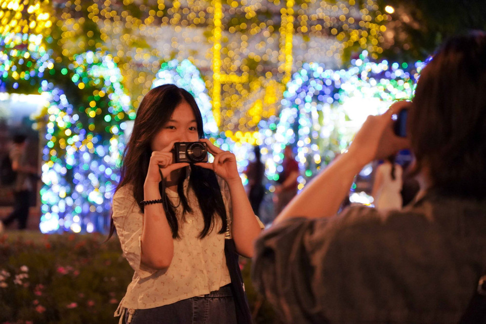 Bạn trẻ tranh thủ ghi lại khoảnh khắc mừng dịp Giáng sinh. (Ảnh: Thu Hương/TTXVN)