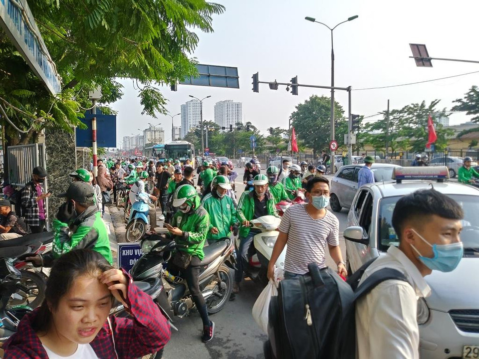 Đông đảo đội ngũ xe ôm công nghệ đứng tràn ra cả lòng đường trước cửa bến xe Giáp Bát để chờ khách. (Ảnh: Việt Hùng/Vietnam+)