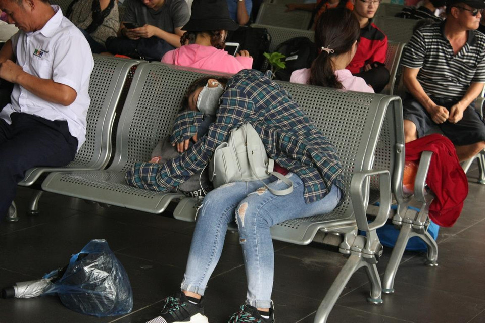 Một hành khách ngủ gục trong nhà chờ sau hành trình bị nhồi nhét và chặt chém giá vé. (Ảnh: Việt Hùng/Vietnam+)