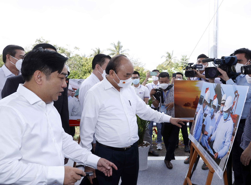 Hình ảnh Chủ tịch nước Nguyễn Xuân Phúc xem trưng bày ảnh quá trình thi công Dự án tuyến đường cao tốc Trung Lương-Mỹ Thuận. (Ảnh: Thống Nhất/TTXVN)