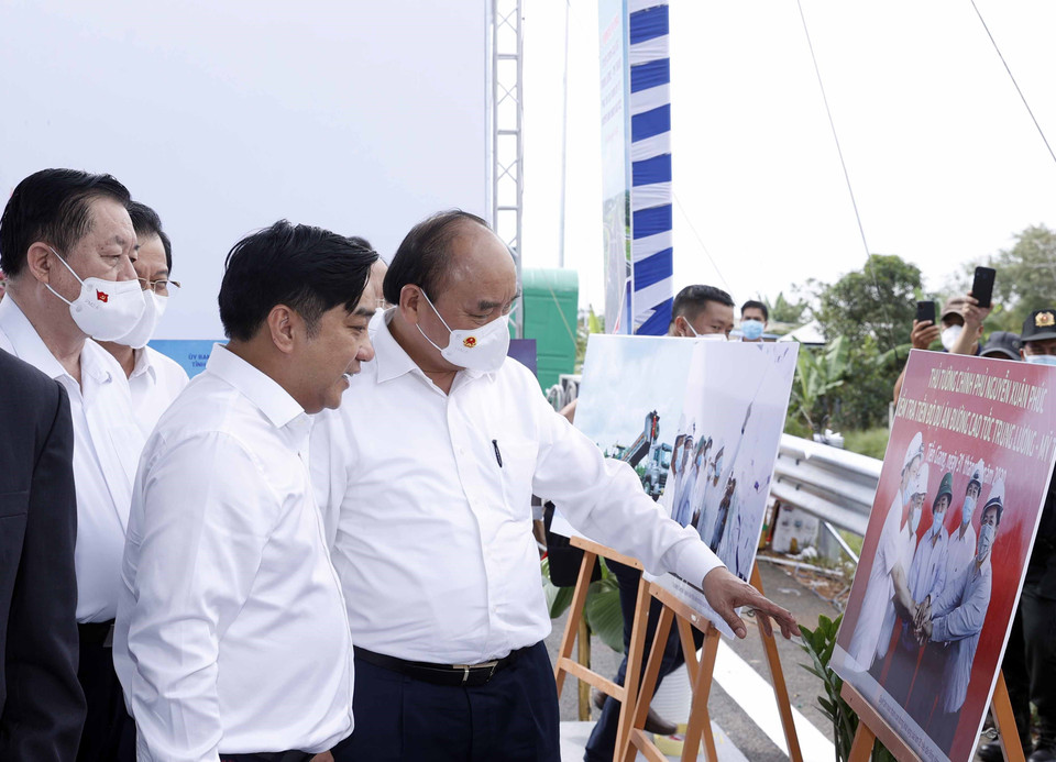 Chủ tịch nước Nguyễn Xuân Phúc xem trưng bày ảnh quá trình thi công Dự án tuyến đường cao tốc Trung Lương-Mỹ Thuận. (Ảnh: Thống Nhất/TTXVN)