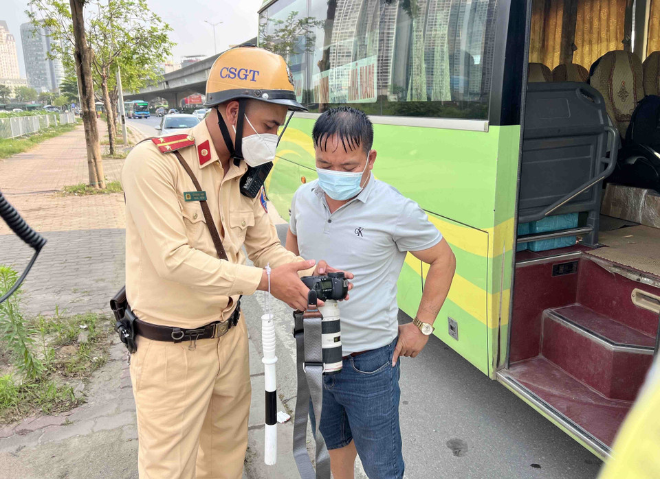 Lực lượng cảnh sát giao thông cho tài xế xem lại hình ảnh vi phạm. (Ảnh: Phạm Kiên/TTXVN)