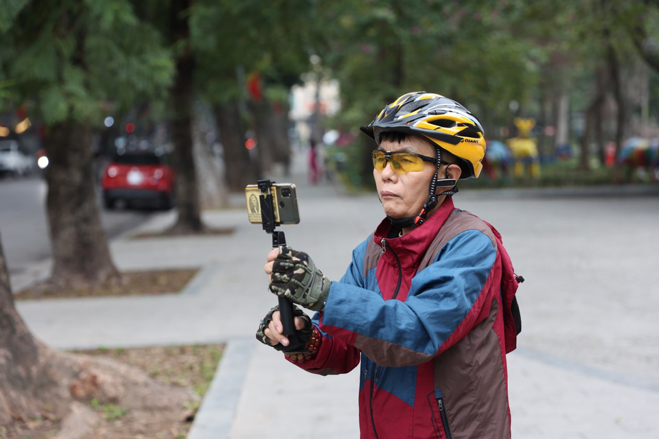 Một cụ già đã lấy điện thoại ra ghi lại khoảnh khắc ngày đầu năm. (Ảnh: Minh Hiếu/Vietnam+)