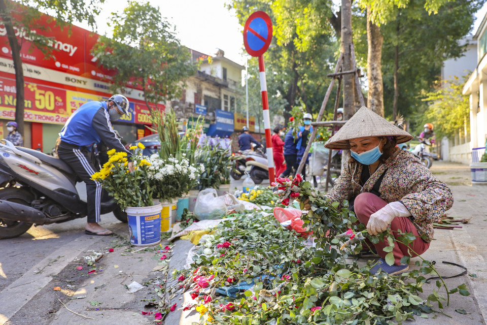 Tiểu thương bán vội những nhành hoa để sớm về ăn Tết, đoàn tụ với gia đình. (Ảnh: Minh Hiếu/Vietnam+)
