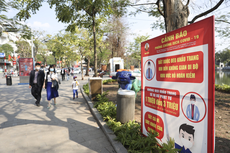 Bên cạnh những tác phẩm nghệ thuật chào đón xuân mới, nhiều tấm biển cảnh báo, nhắc nhở người dân thường xuyên đeo khẩu trang vẫn được bố trí quanh hồ Hoàn Kiếm. (Ảnh: Minh Hiếu/Vietnam+)