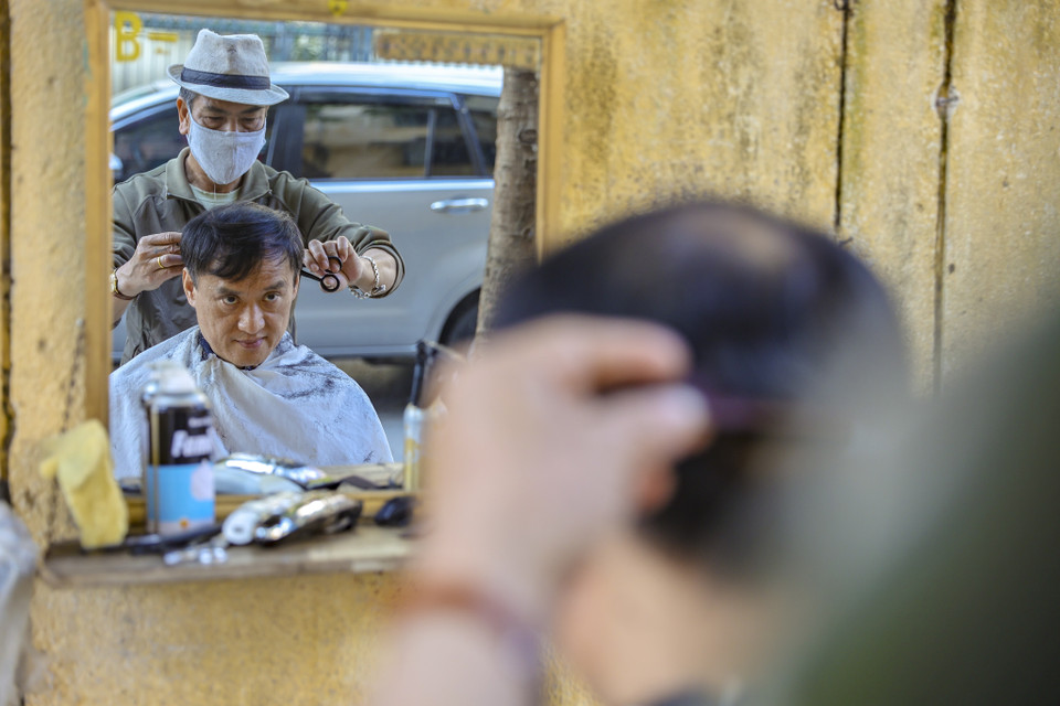 Chú Bình, thợ cắt tóc trên đường Phan Huy Chú vẫn đang phục vụ những vị khách của mình trong ngày giáp Tết. (Ảnh: Minh Hiếu/Vietnam+)