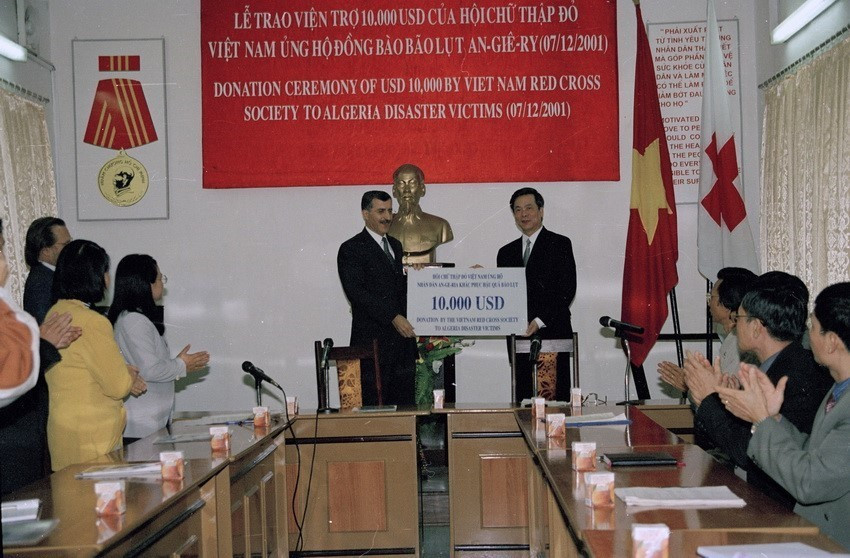 Phó giáo sư Nguyễn Văn Thưởng - Phó Chủ tịch Hội Chữ thập Đỏ Việt Nam, trao tiền ủng hộ nhân dân Algieria cho đại sứ đặc mệnh toàn quyền Algieria tại Việt Nam Tewwfik Abada (2001). (Ảnh: Hữu Oai/TTXVN)