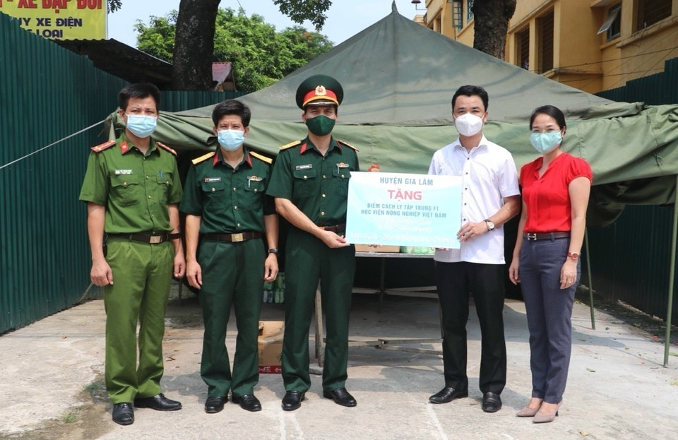 Lãnh đạo huyện Gia Lâm cùng Hội Chữ thập Đỏ huyện trao tượng trưng phần hỗ trợ tới khu cách ly tập trung phòng chống dịch COVID-19 của Học viện Nông nghiệp. (Ảnh: TTXVN phát)