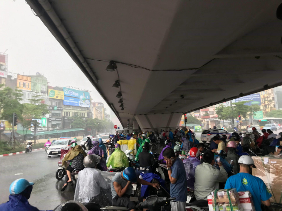 Mưa lớn khiến nhiều người phải trú mưa dưới chân cầu vượt ở Ngã Tư Sở làm tắc cả một đoạn đường Láng. (Ảnh: Trọng Đạt/TTXVN)
