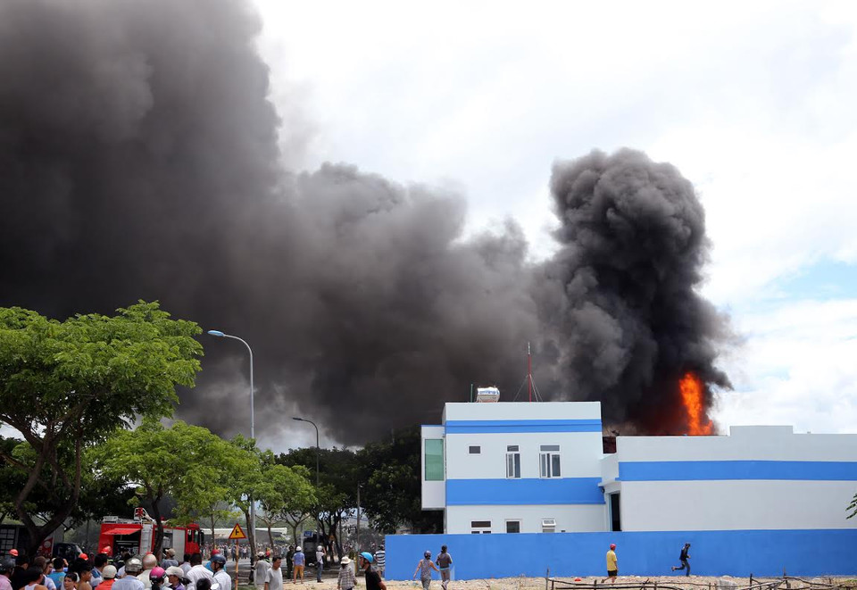 Đến 12 giờ 30 cùng ngày đám cháy vẫn bùng cháy dữ dội kèm theo những tiếng nổ lớn phát ra và cột khói đen kịt bốc cao hàng chục mét. (Nguồn: Trần Lê Lâm/Vietnam+)