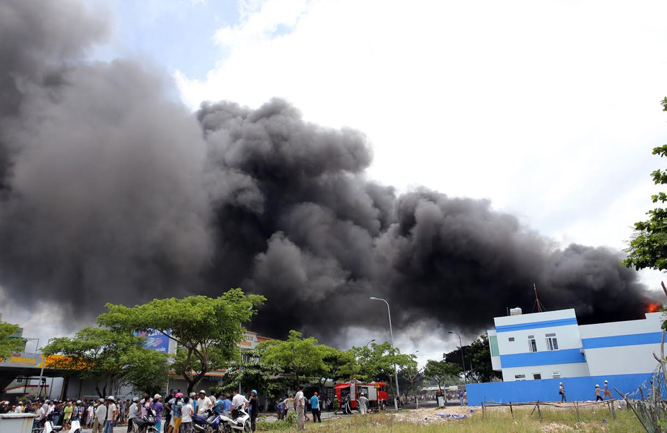 Đến 12 giờ 30 cùng ngày đám cháy vẫn bùng cháy dữ dội kèm theo những tiếng nổ lớn phát ra và cột khói đen kịt bốc cao hàng chục mét. (Nguồn: Trần Lê Lâm/Vietnam+)