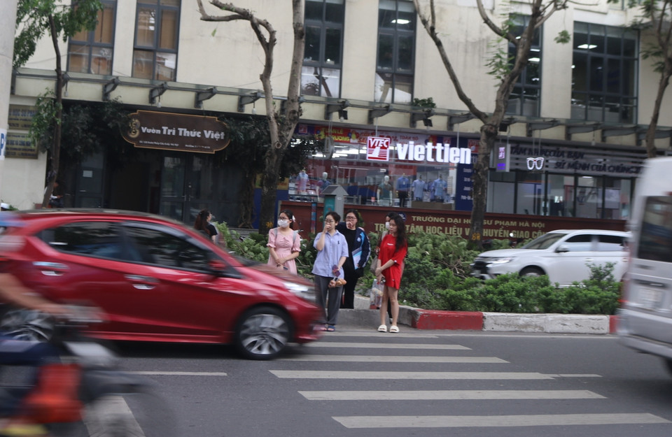 Tuy nhiên, nhiều người đi bộ vẫn phải dõi mắt để len qua dòng phương tiện không chấp hành hiệu lệnh của đèn tín hiệu. (Ảnh: Nguyễn Minh Hằng/Vietnam+)