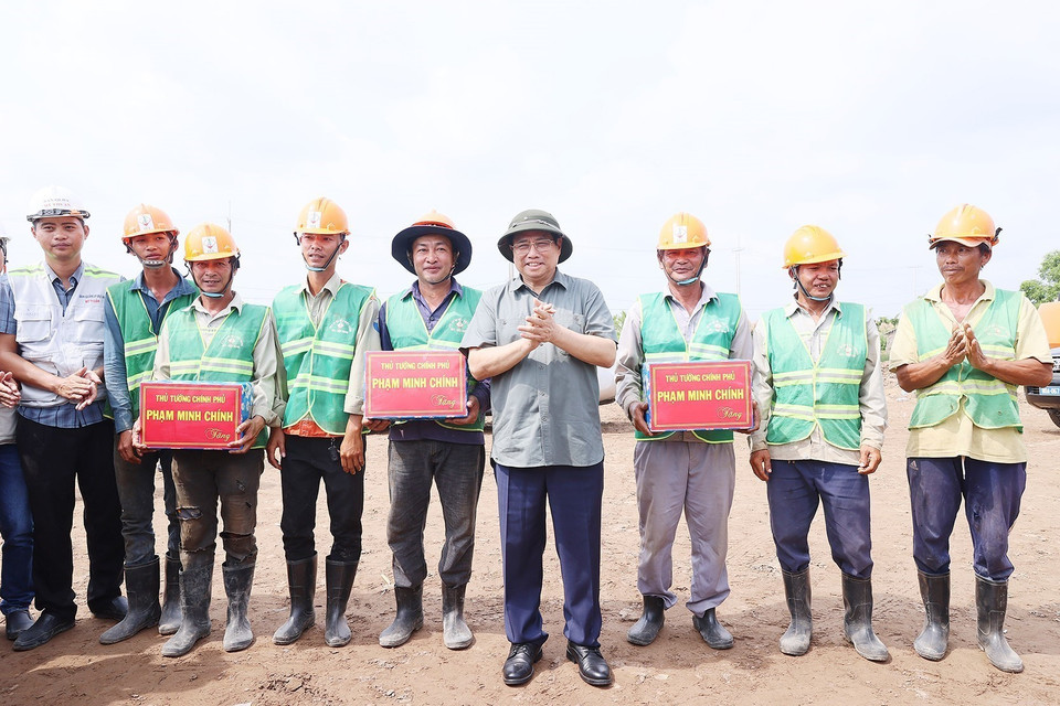 Thủ tướng Phạm Minh Chính tặng quà cho công nhân Dự án Đường bộ Cao tốc Cà Mau-Cần Thơ. (Ảnh: Dương Giang/TTXVN)
