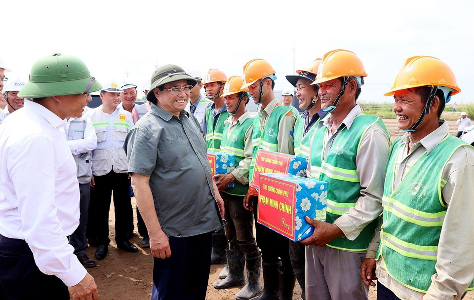 Thủ tướng Phạm Minh Chính tặng quà cho công nhân Dự án Đường bộ Cao tốc Cà Mau-Cần Thơ. (Ảnh: Dương Giang/TTXVN)
