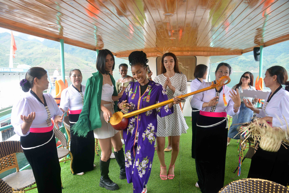 Các thí sinh của cuộc thi Hoa hậu Du lịch Thế giới 2022 cùng đồng bào dân tộc Thái trải nghiệm du lịch lòng hồ huyện Quỳnh Nhai. (Ảnh: Quang Quyết/TTXVN)