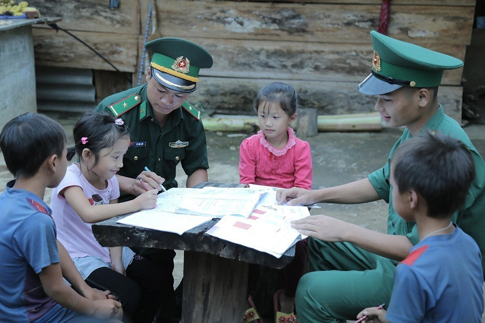 Cán bộ, chiến sỹ Đồn Biên phòng Mường Cai, tỉnh Sơn La - những thầy giáo “mang quân hàm xanh” hướng dẫn trẻ em vùng biên giới học bài. (Ảnh: Hữu Quyết/TTXVN)