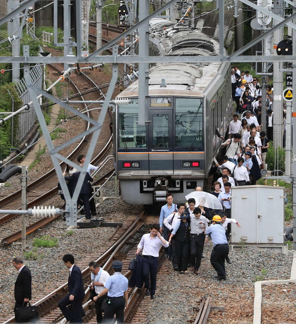 Hành khách sơ tán khỏi tàu hỏa sau trận động đất tại Osaka, Nhật Bản ngày 18/6. (Ảnh: AFP/TTXVN)