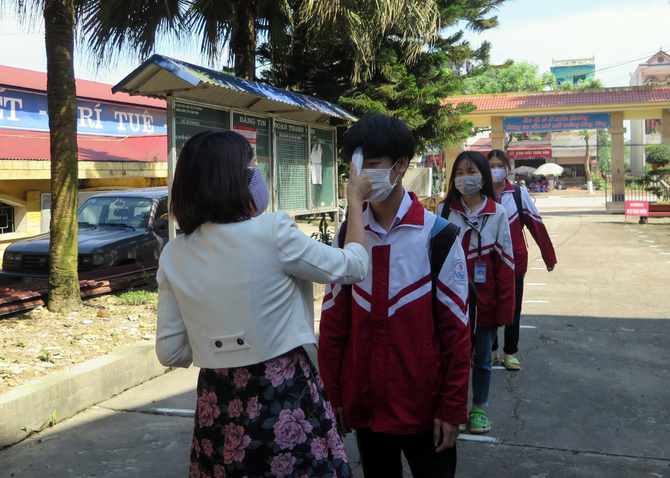 Học sinh khối 12 Trường THPT Sông Công, thành phố Sông Công, tỉnh Thái Nguyên, đo thân nhiệt trước khi vào trường. (Ảnh: Thu Hằng/TTXVN)