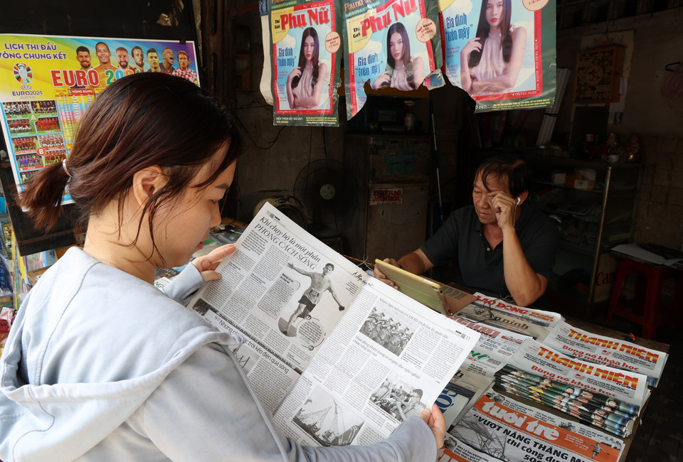 Khách mua báo tại sạp báo giấy ở quận Phú Nhuận. (Ảnh: Hồng Đạt/TTXVN)