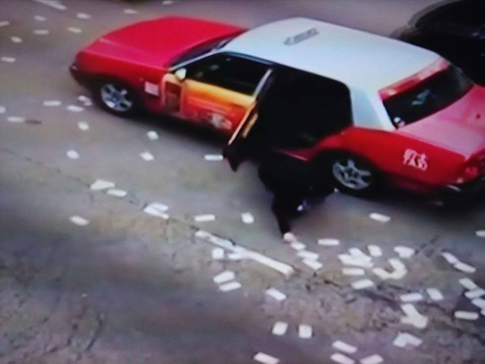 Lái xe taxi dừng xe giữa đường để chạy xuống nhặt tiền. (Nguồn: CCTV)