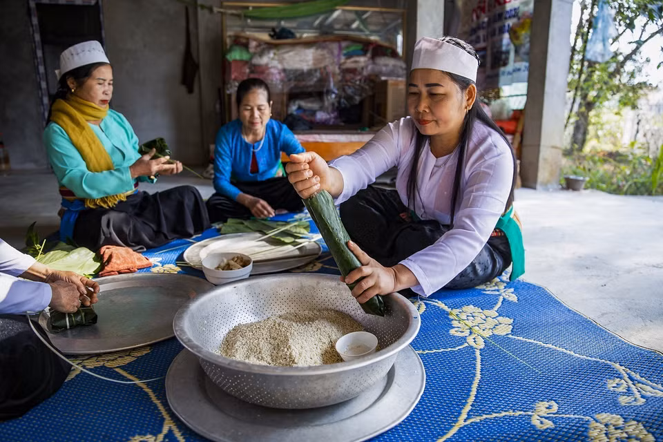 Những người phụ nữ Mường tham gia gói bánh chưng và bánh ống chuẩn bị đón tết. (Ảnh Trọng Đạt/TTXVN)