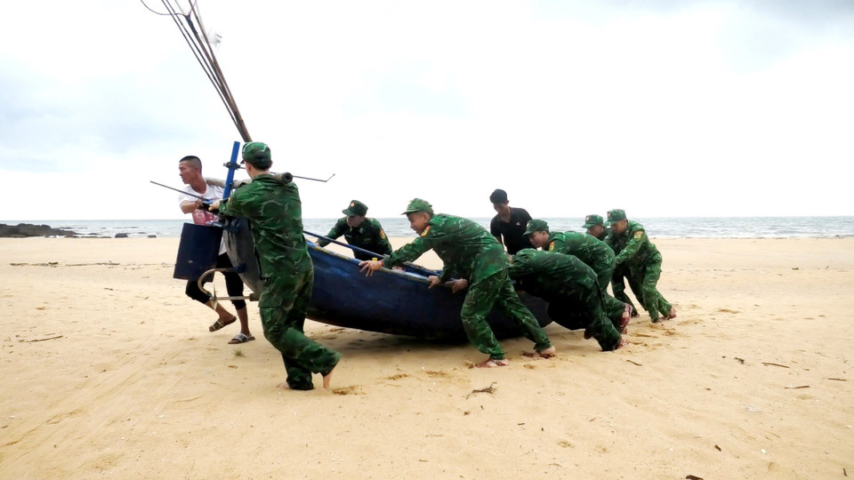 Cán bộ, chiến sỹ Đồn Biên phòng Lý Hòa (Bộ đội Biên phòng Quảng Bình) giúp ngư dân xã Đức Trạch, huyện Bố Trạch đưa thuyền lên bờ tránh trú. (Ảnh: TTXVN phát)