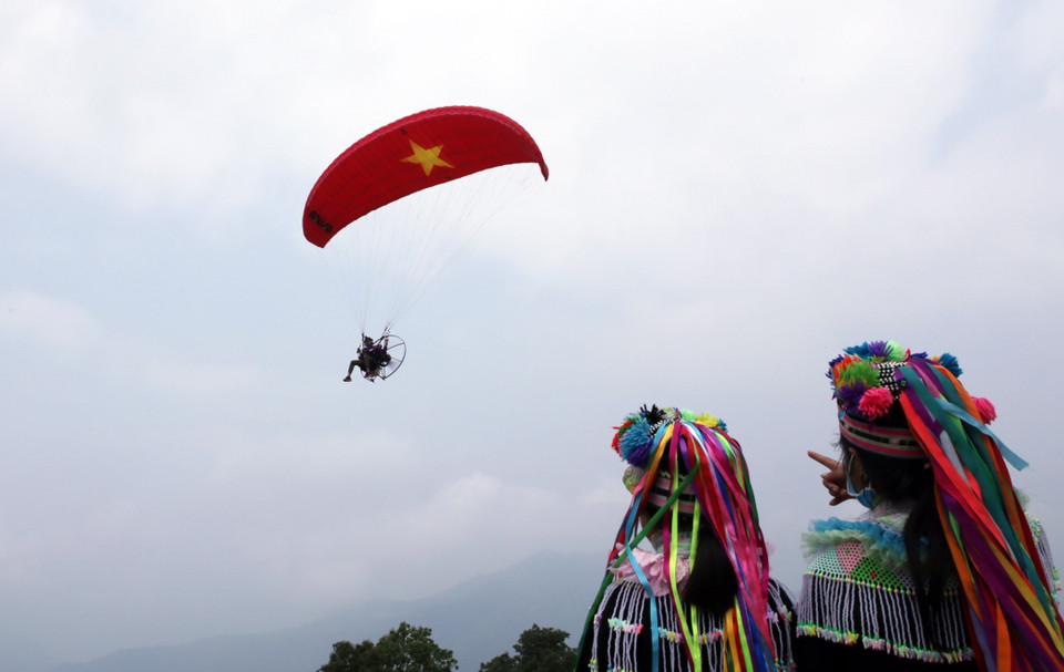 Du khách thích thú xem dù lượn trên đỉnh dãy núi Hoàng Liên Sơn ở khu vực bản Sì Thâu Chải. (Ảnh: Quý Trung/TTXVN)