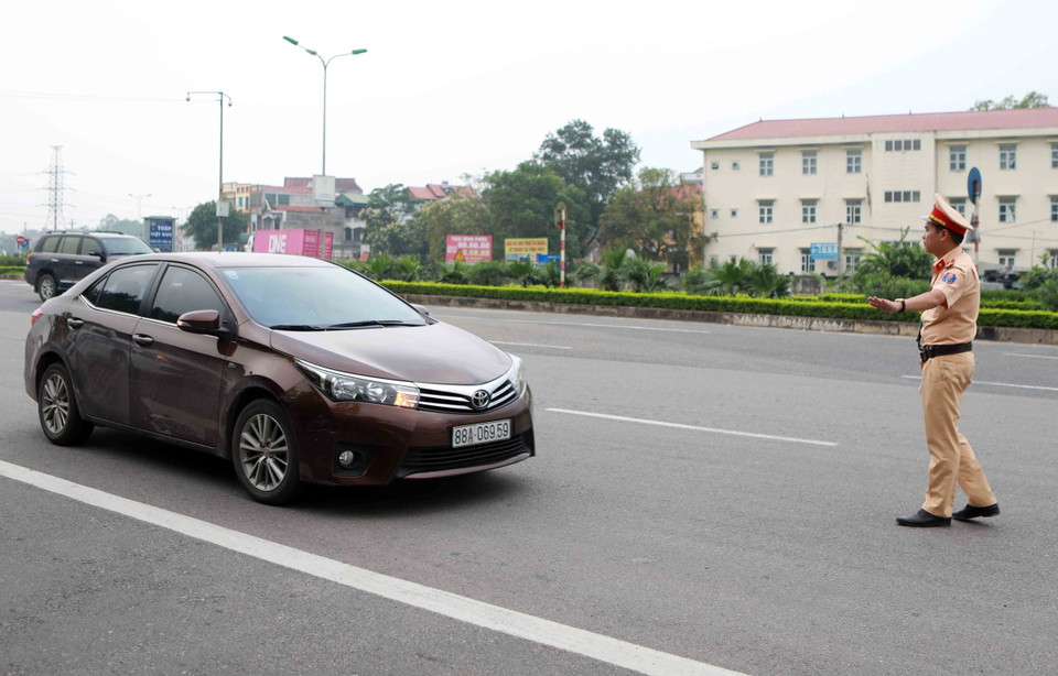 Cảnh sát giao thông tỉnh Vĩnh Phúc ra hiệu lệnh dừng phương tiện để kiểm tra trong ngày ra quân tại khu vực Trạm thu phí đường bộ quốc lộ 2 đoạn đi qua thành phố Vĩnh Yên. (Ảnh: Hoàng Hùng/TTXVN)