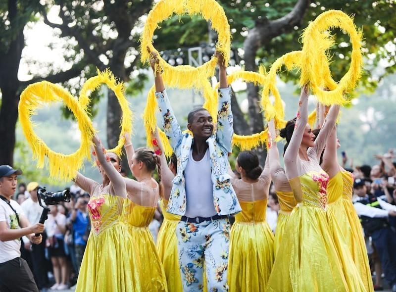 Các nghệ sỹ quốc tế trong trang phục rực rỡ và âm nhạc rộn ràng biểu diễn và diễu hành trên phố đi bộ Hồ Gươm.(Ảnh: Thanh Tùng/TTXVN)