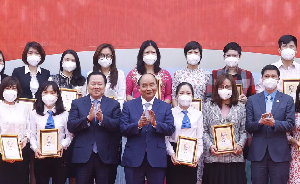 Hình ảnh Chủ tịch nước Nguyễn Xuân Phúc tặng ảnh chân dung Chủ tịch Hồ Chí Minh cho các cá nhân có thành tích xuất sắc của Tập đoàn Dệt may Việt Nam. (Ảnh: Thống Nhất/TTXVN)