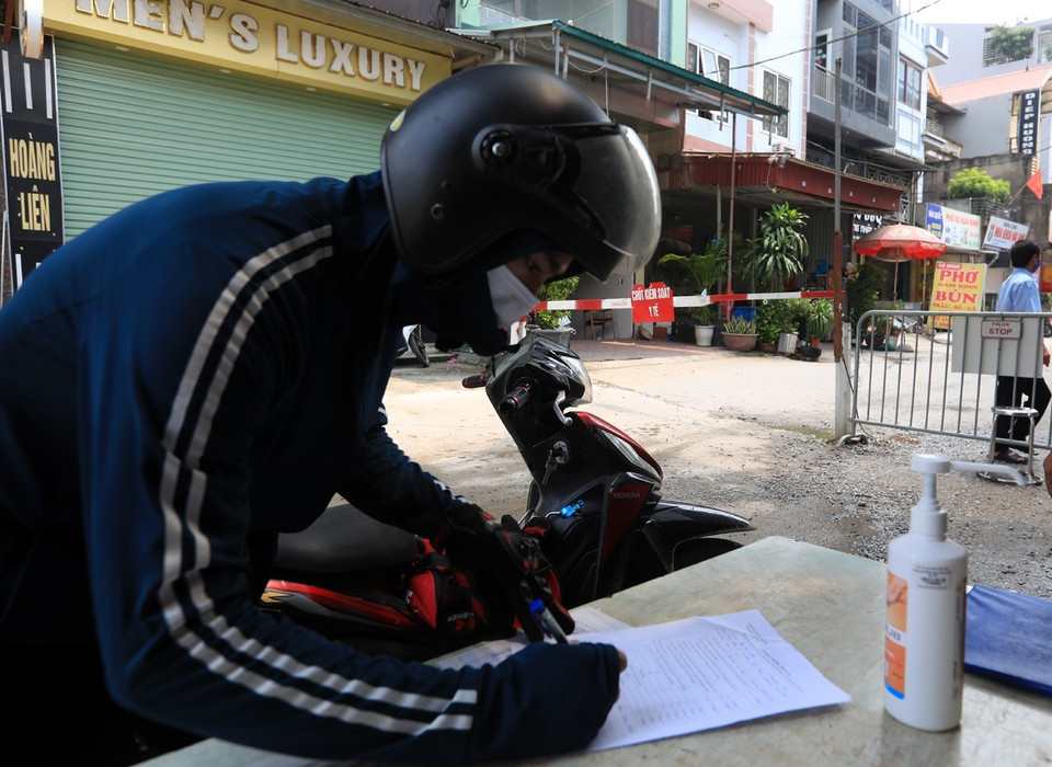 Các công nhân muốn đi mua thực phẩm đều phải khai báo y tế khi qua chốt kiểm soát y tế tai thôn Bầu, xã Kim Chung, Đông Anh. (Ảnh: Phan Tuấn Anh/TTXVN)