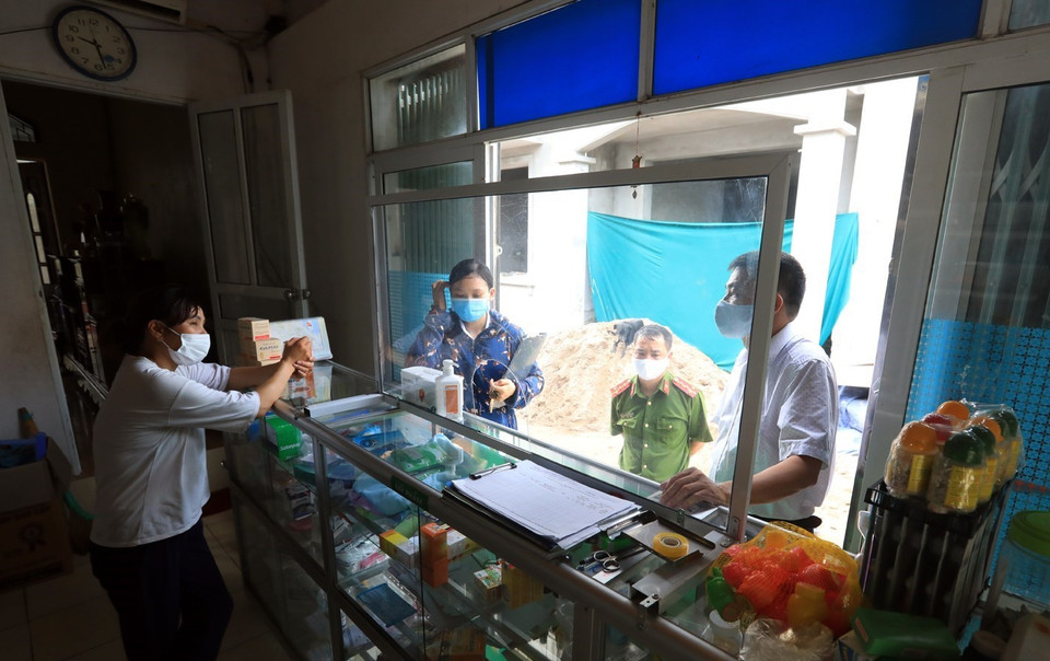 Các lực lượng chức năng thị trấn Quang Minh kiểm tra, nhắc nhở các hộ dân thực hiện, tuân thủ các biện pháp giãn cách xã hội và đảm bảo công tác phòng chống dịch COVID-19. (Ảnh: Phan Tuấn Anh/TTXVN)