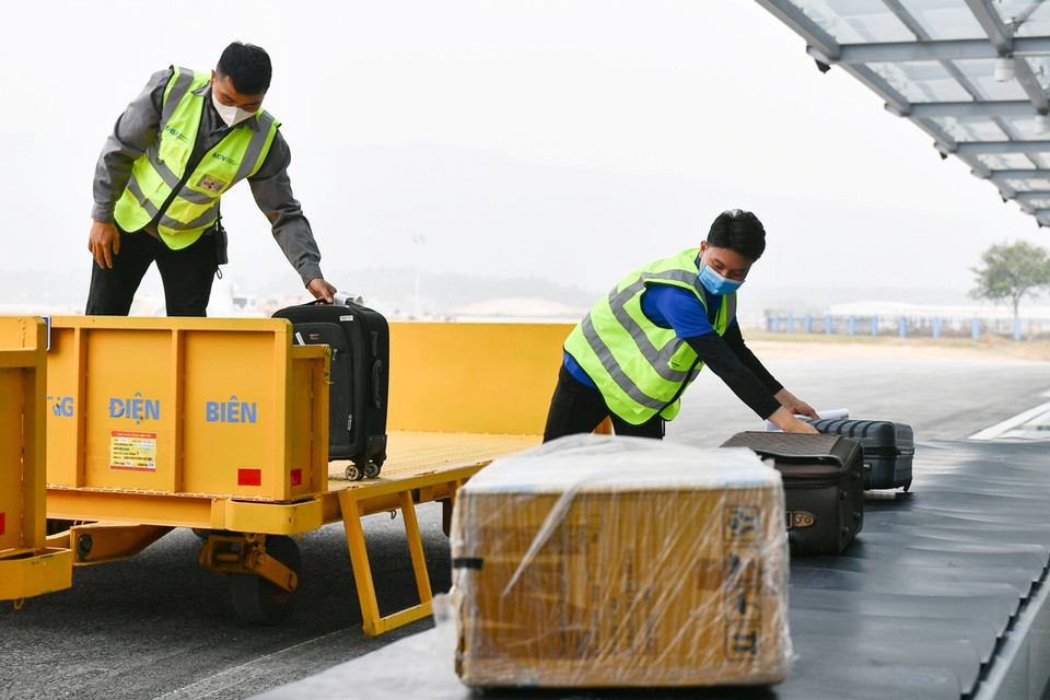 Nhân viên bốc xếp phân loại hành lý tại đảo đi và bốc lên phương tiện vận chuyển hành lý quá khổ. (Ảnh: PV/Vietnam+)