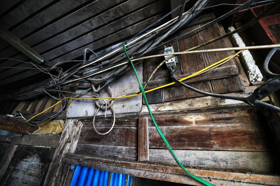 Hệ thống điện chạy ép sát phần mái nhà gỗ này, chỉ cần sự sơ ý của người dân là có thể gây hỏa hoạn chết người, đặc biệt trong mùa nắng nóng. (Ảnh: Thành Đạt/TTXVN)