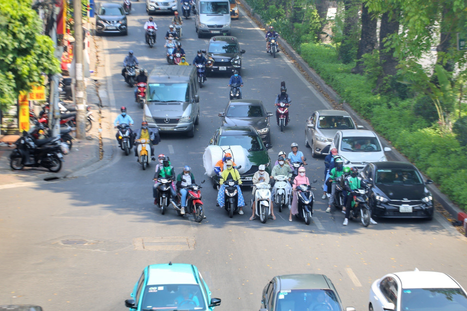 Tại đường Láng, nhiều người tụ lại trong bóng râm chờ đèn đỏ gây cản trở giao thông. (Ảnh: Tuấn Đức/TTXVN)