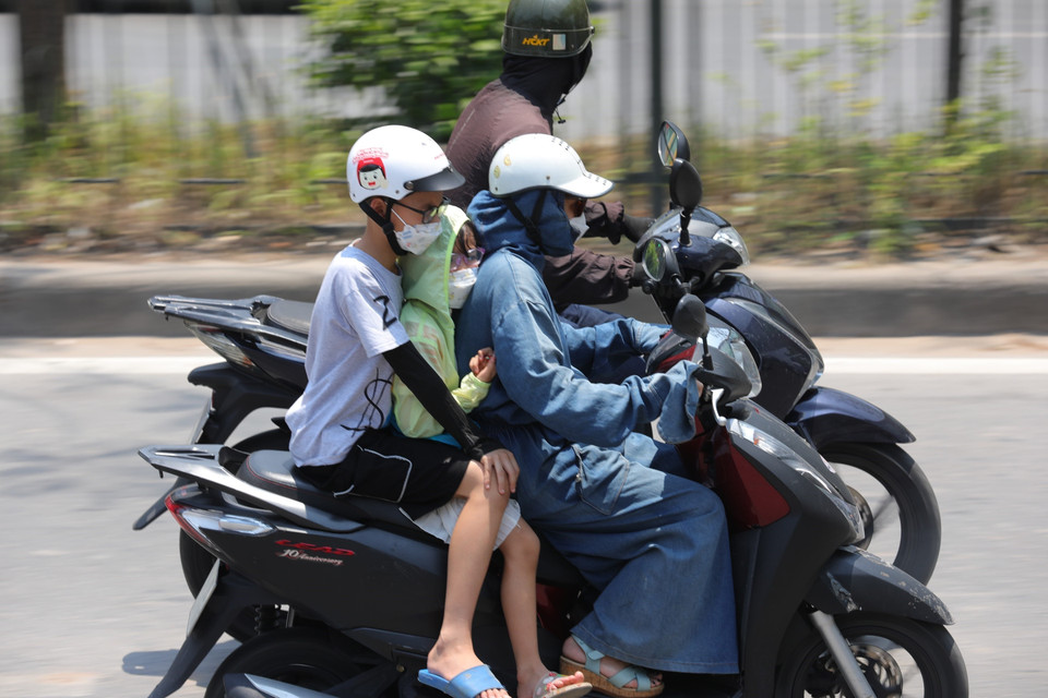 Che chắn kỹ càng khi phải di chuyển trên đường Giải Phóng lúc 11h30. (Ảnh: Hoàng Hiếu/TTXVN)