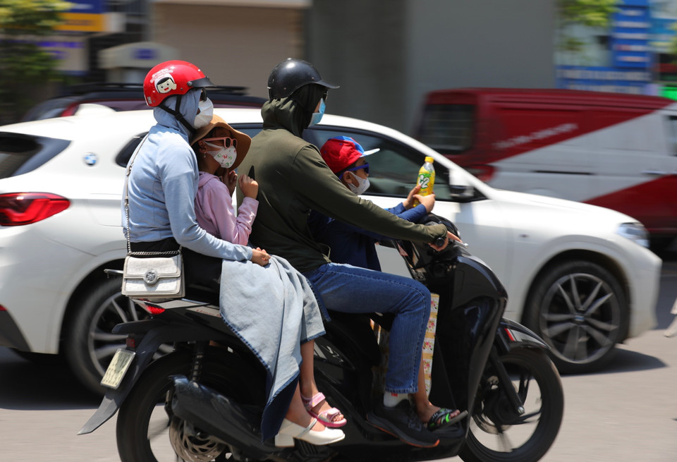 Hầu hết người di chuyển ngoài trời đều trang bị áo, găng, mũ chống nắng nóng. (Ảnh: Hoàng Hiếu/TTXVN)