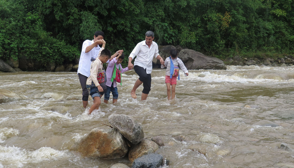Giáo viên và học sinh trường Tiểu học số 2 xã Nậm Xe, huyện Phong Thổ, tỉnh Lai Châu băng qua suối để tới lớp học. (Ảnh: Việt Hoàng/TTXVN)