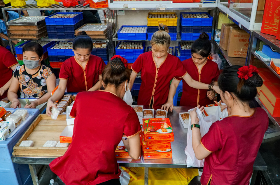 Nhân viên quán đang hối hả đóng bánh vào túi phục vụ khách tới mua hàng. (Ảnh: Minh Hiếu/Vietnam+)