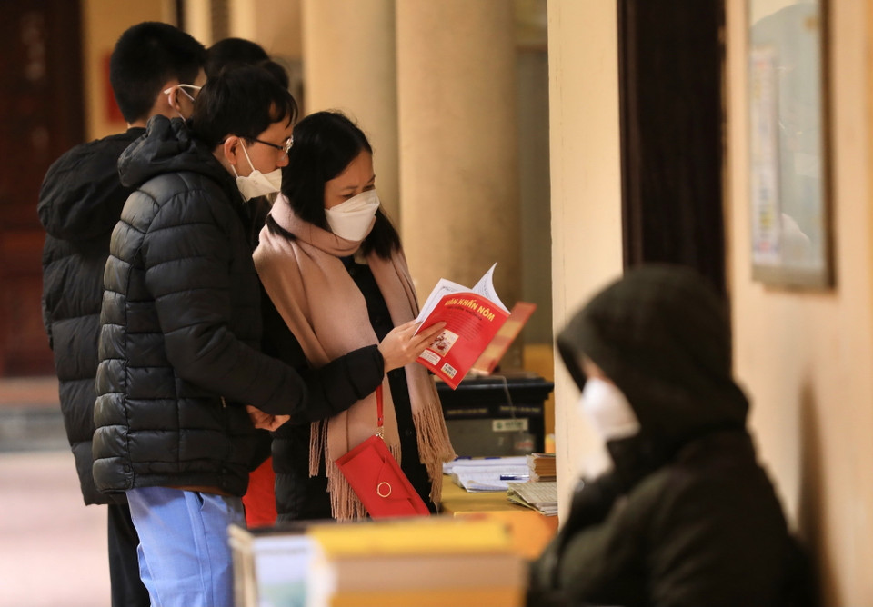 Người dân xem sách khi đến lễ tại chùa Quán Sứ sáng 13/2.(Ảnh: Hoàng Hiếu/TTXVN)